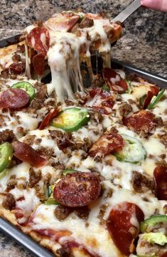 a person taking a slice of pizza from a pan