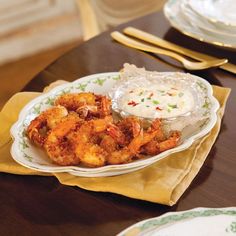 a plate filled with shrimp and rice on top of a table next to silverware