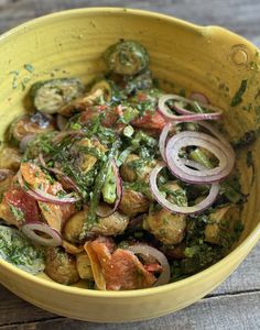 a yellow bowl filled with vegetables on top of a wooden table