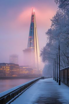 a very tall building sitting next to a body of water covered in snow and ice