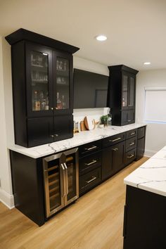 an empty kitchen with black cabinets and marble counter tops, wood flooring and wooden floors