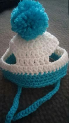 a blue and white crocheted hat sitting on top of a bed