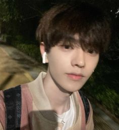 a young man with ear buds on his ears standing in front of a road at night