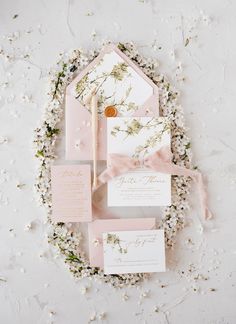 the wedding stationery is laid out on top of flowers