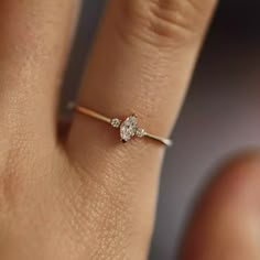 a woman's hand with a diamond ring on top of her finger, showing the side view