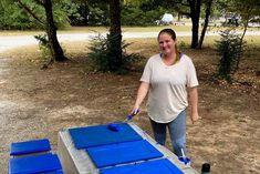 a woman standing next to a table with blue doors on it in the middle of a park