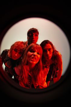 a group of young people standing next to each other in front of a round window