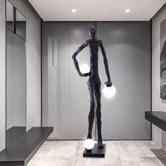 a black and white photo of a statue in a room with two lights on the floor