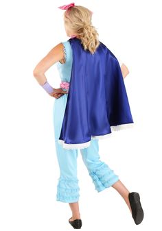 a woman in a blue cape and matching pants is standing with her back to the camera