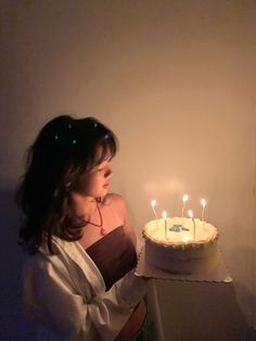 a woman holding a cake with lit candles