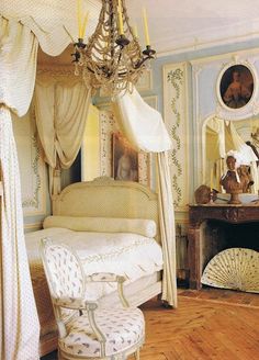 a bedroom with a canopy bed, chandelier and mirror on the wall above it