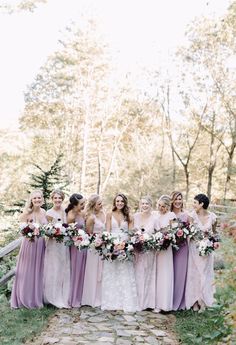 a group of women standing next to each other holding bouquets in their hands and smiling at the camera