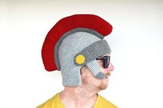 a man wearing a knitted hat with a red circle on the side and a yellow t - shirt underneath