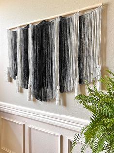 three black and white curtains hanging on the wall next to a potted plant