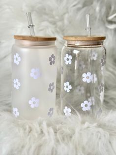 two glass jars with flowers painted on them are sitting on a furnishing area