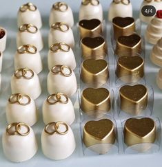 wedding rings and heart shaped chocolates are on display in plastic containers with gold foil