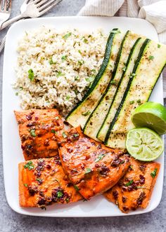 grilled salmon, rice and zucchini on a white plate with a fork