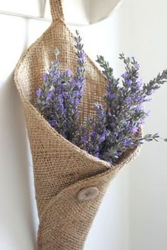 a bouquet of lavenders wrapped in burlock hanging from a hook on a wall