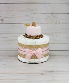 a three tiered cake with pink and gold decorations on top, sitting on a wooden table