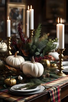 a dining room table decorated with white pumpkins, greenery and gold candlesticks