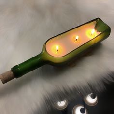 a green bottle with candles in it sitting on top of a white fur covered floor