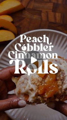 a person holding up a piece of food on top of a white plate with peach cobbler cinnamon rolls