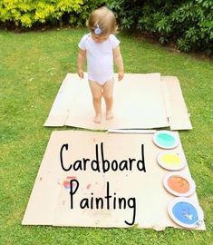 a toddler standing on top of a cardboard board with the words cardboard painting