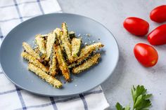 some fried food on a plate next to tomatoes and parmesan sprinkles