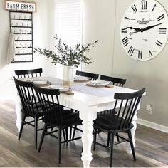 a white table with black chairs and a clock on the wall