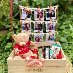 a teddy bear sitting in a wooden box with photos hanging on the clothesline and some candies