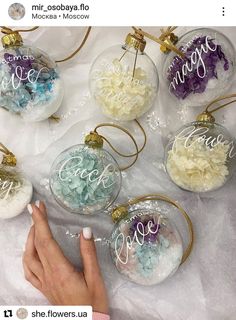 a person's hand is pointing at some glass ornaments with the word peace on them