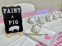 some pig figurines are on a table with a sign that says paint a pig