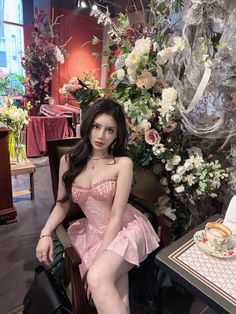 a woman is sitting on a chair in front of flowers