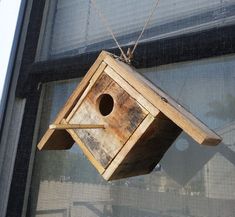 a wooden birdhouse hanging from the side of a window