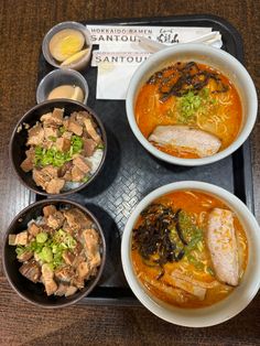 there is a tray with different types of food in bowls and sauces on it