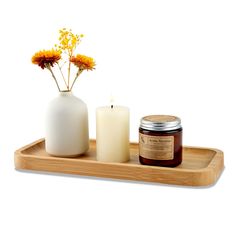 a candle and some flowers on a wooden tray