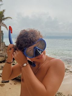 a woman wearing goggles and snorkels on the beach near the ocean