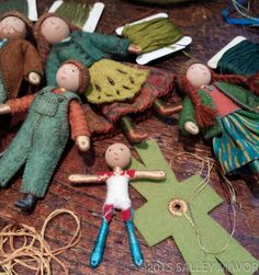 several wooden dolls are arranged on a table with scissors and other crafting supplies around them