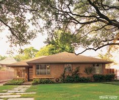 a small brick house sitting on top of a lush green field next to a tree