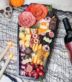 a tray filled with different types of cheese and meats next to a bottle of wine