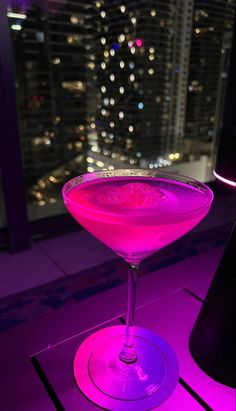 a pink drink sitting on top of a table in front of a cityscape