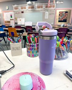 a purple tumbler sitting on top of a white table next to a pink plate