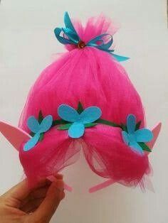 a hand holding up a pink wig with blue flowers on it