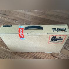 an unopened box sitting on top of a wooden floor next to a pair of scissors