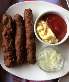 some fried food on a white plate with ketchup and mayonnaise next to it