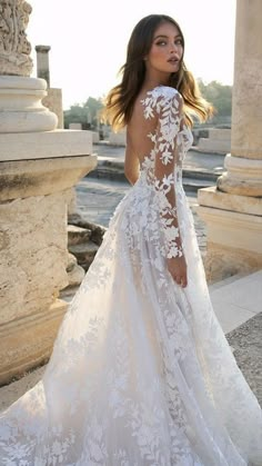 a woman in a white wedding dress standing on the street with her back to the camera