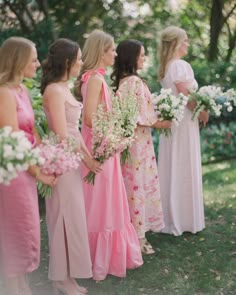 a group of women standing next to each other in dresses and holding bouquets on the grass