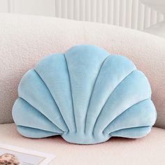 a blue shell shaped pillow sitting on top of a white couch