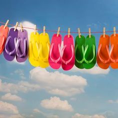 colorful flip flops hanging on a clothesline against a blue sky and white clouds