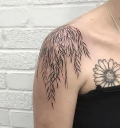 a woman's arm with a flower and bamboo tree tattoo on her left shoulder